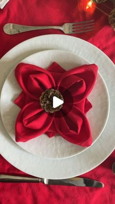 a white plate topped with a red flower next to silverware and utensils