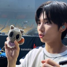 a young man holding a stuffed animal in his right hand and looking at the camera