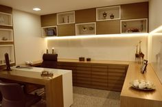 an office with desk, chairs and shelves on the wall above it is lit by recessed lighting