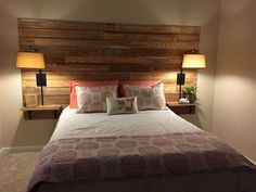 a bed with two lamps on either side of the headboard and pillows on it