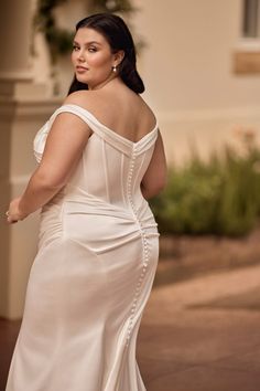 a woman in a white dress posing for the camera with her hand on her hip