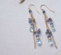 "Our super-glam version of the Waterfall Earring. We have chosen three lengths of chain in either 14K Gold Fill or Sterling Silver and interspersed them with delicate bundles of faceted Iolite Rondelles and a single Rondelle at the top. The chains are then finished with another Rondelle and a faceted Aquamarine tear drop. The effect is nothing less than stunning. Each gemstone is hand wrapped in either 14K Gold-Filled or Sterling Silver Wire before being added to the chain and ear wire in coordi Cheap Dangle Earrings With Faceted Beads, Aquamarine Earrings, Beaded Drop Earrings, March Birthstone, Earrings Dainty, Fashion Jewelry Earrings, Earrings Drop, Earrings Blue, Cluster Earrings