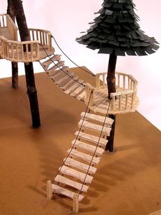 a wooden staircase leading to a tree on top of a table next to a lamp