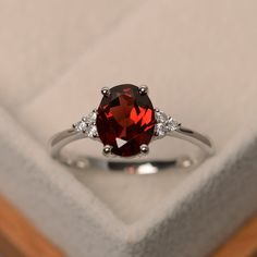 a ring with a red stone surrounded by white diamonds