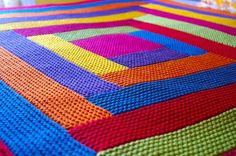 a multicolored crocheted blanket on a bed