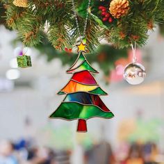 a glass christmas tree ornament hanging from a pine tree with ornaments around it