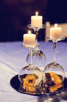 two wine glasses with sunflowers in them are sitting on a plate that is decorated with candles