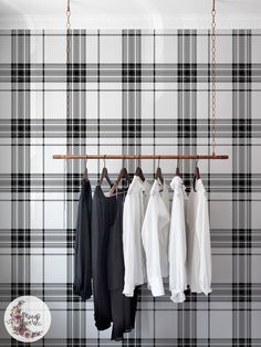 four shirts hanging on a rail in front of a plaid wallpapered wall and coat rack