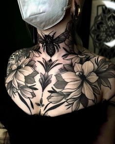 a woman with tattoos on her chest wearing a face mask