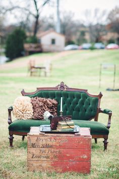 an old trunk sitting on top of a grass covered field next to a green couch