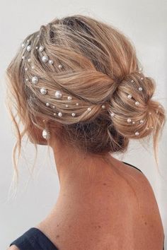 a woman with her hair in a low bun and pearls on the back of her head