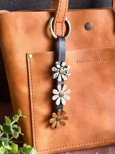 a brown leather bag with flowers attached to it