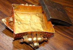 an old metal object sitting on top of a wooden table next to a large knife