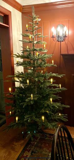 a small christmas tree with lit candles in the center is on a dining room table