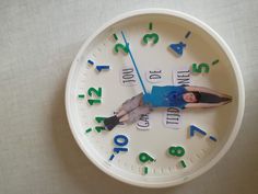 a white clock with a woman laying on it's face in front of numbers