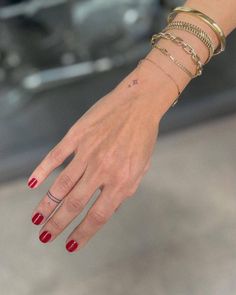 a woman's hand with four different bracelets on her wrist and one has a cross tattoo on it