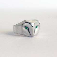 The lovely addition to our minimalist and perfectly geometric sterling silver Barn Owl Ring, and Barn Owl ring with blue Sapphire eyes. Beautiful setting of 2 vibrant green Emerald stones { 1.8 mm each). Designed by jewelry maker Elina Gleizer, this gorgeous ring subtly represents the ancient wisdom of the owl symbol without coming across as elementary in the design. Its strength is its simplicity. The thick sterling silver wraps comfortably around the wearers finger with the owl's face looking Ring Geometric, Sapphire Eyes, Ring With Emerald, Owl Ring, Emerald Eyes, Jewellery Unique, Owl Jewelry, Silver Jewelry Rings, Jewelry Choker