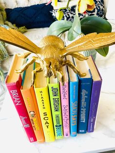 a golden bird figurine sitting on top of a stack of books