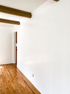 an empty room with white walls and wood floors is seen in this image from the doorway