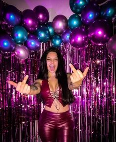 a woman is posing in front of purple and blue balloons with her hands out to the side