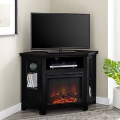 a flat screen tv sitting on top of a black entertainment stand next to a fire place