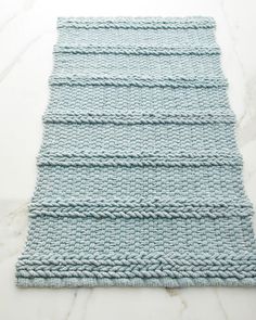 a blue knitted rug sitting on top of a marble floor