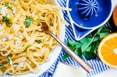 a white plate topped with pasta next to oranges