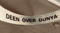 a close up of a white ribbon with black writing on it that says,'deen over dunya '