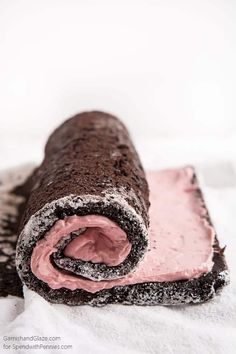 a chocolate roll with pink frosting on it sitting on top of a white towel