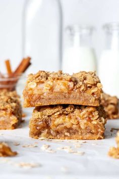 three granola bars stacked on top of each other with cinnamon sticks in the background