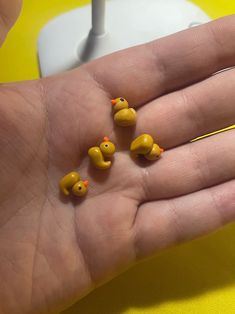 four yellow rubber ducks sitting on the palm of someone's hand