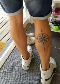 a person with a compass tattoo on their leg, standing in front of a door