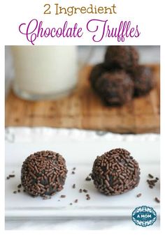 two chocolate truffles on a white plate with milk and strawberries in the background