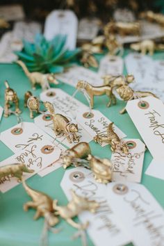 small gold figurines sitting on top of a table next to tags with names