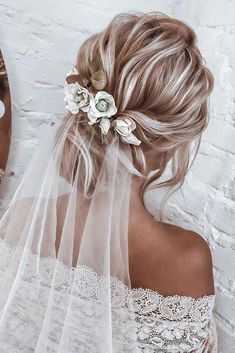 a woman wearing a veil with flowers in her hair is looking at herself in the mirror