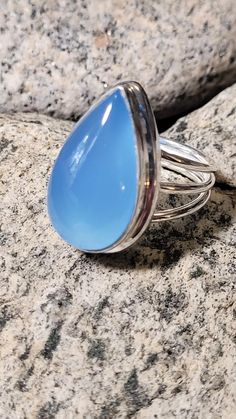 This is a sterling silver ring. These rings are old store stock- unworn. The stone is blue chalcedony, a type of quartz, That is very "glowy" and is about one inch tall. It reminds me of a the sky on a clear bluebird day. This stone has traditionally been used for for calmness, and serenity.  This retailed at $96. It comes in a tiny ring box. Blue Chalcedony Cabochon Rings, Blue Cabochon Teardrop Ring, Blue Teardrop Cabochon Rings, Blue Moonstone Cabochon Ring, Tiny Rings, Blue Chalcedony, One Inch, Bluebird, Ring Box