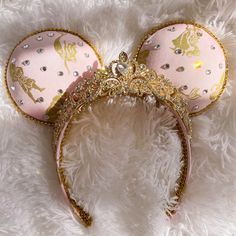 a pink and gold minnie mouse ears headband laying on top of a fluffy white blanket