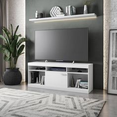 a living room with a large television on top of a white entertainment center next to a potted plant