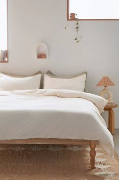 a bed with white sheets and pillows in a room