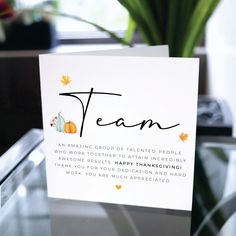 a greeting card with the words team on it sitting on a table next to a potted plant