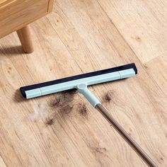 a mop laying on the floor next to a wooden table with a chair in the background