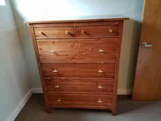 a wooden dresser sitting next to a door in a room with carpeted flooring