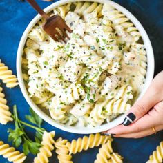 a person holding a fork over a bowl of pasta