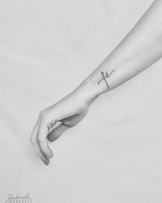 a person with a small cross tattoo on their left wrist holding the hand of another person