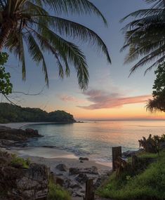 the sun is setting over the ocean and beach with steps leading to the water's edge