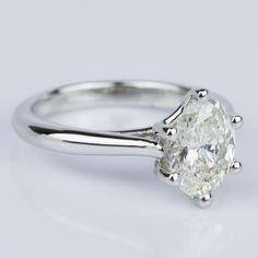 a white gold engagement ring with an oval cut diamond in the center and two clawed shoulders