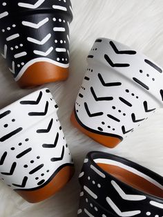 four black and white cups with orange rims sitting on top of a fur covered floor