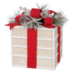 a red and white gift box with a bow on it's side, decorated with pine branches