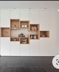 an empty room with white walls and wooden shelvings on the wall next to a black tile floor