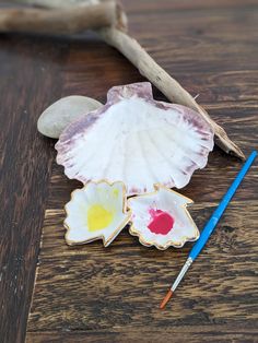 seashells and paint are sitting on a wooden table